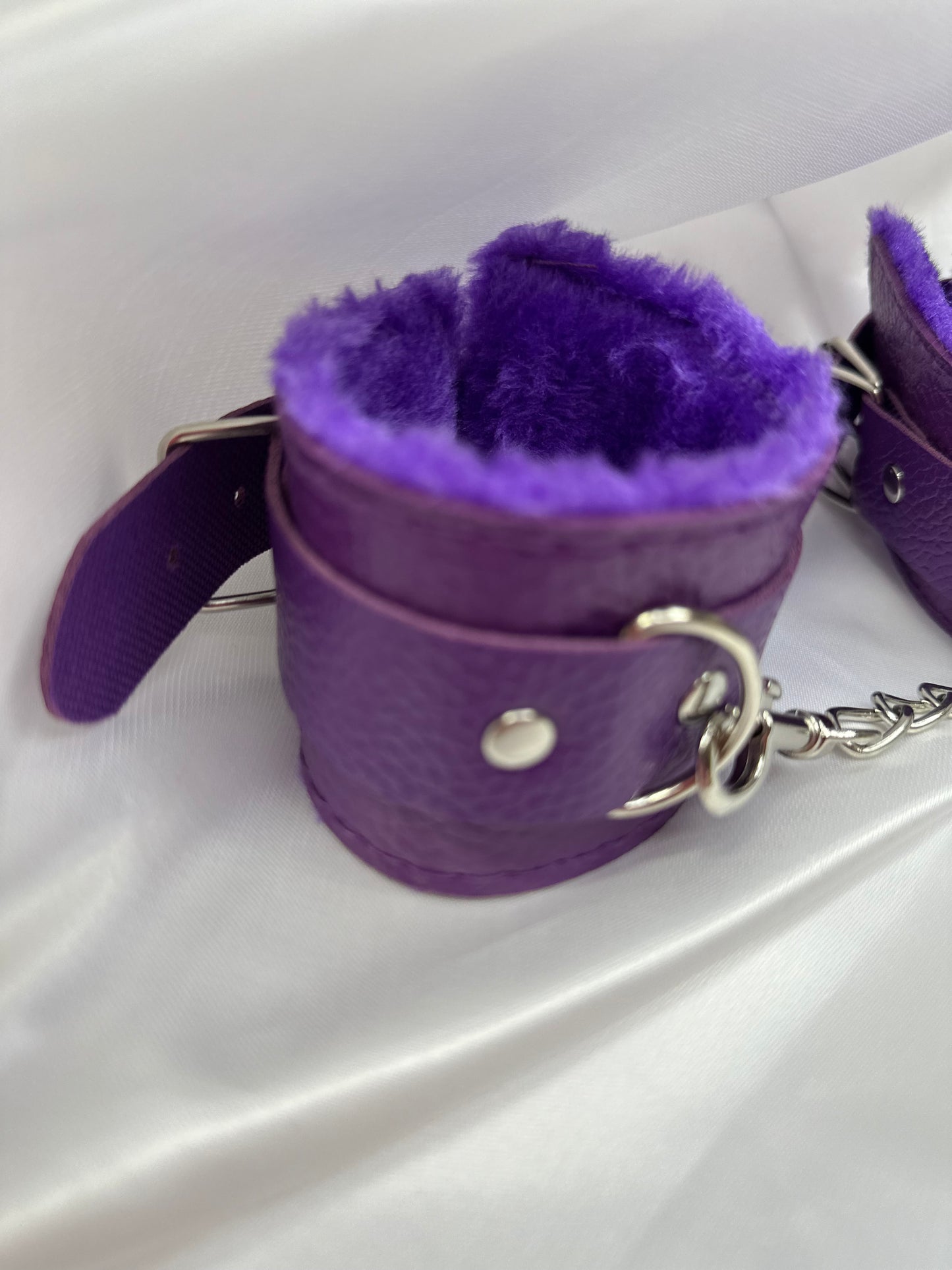 Purple soft faux leather handcuffs with adjustable buckle closure and sturdy metal hardware, perfect for BDSM, roleplay, and cosplay.