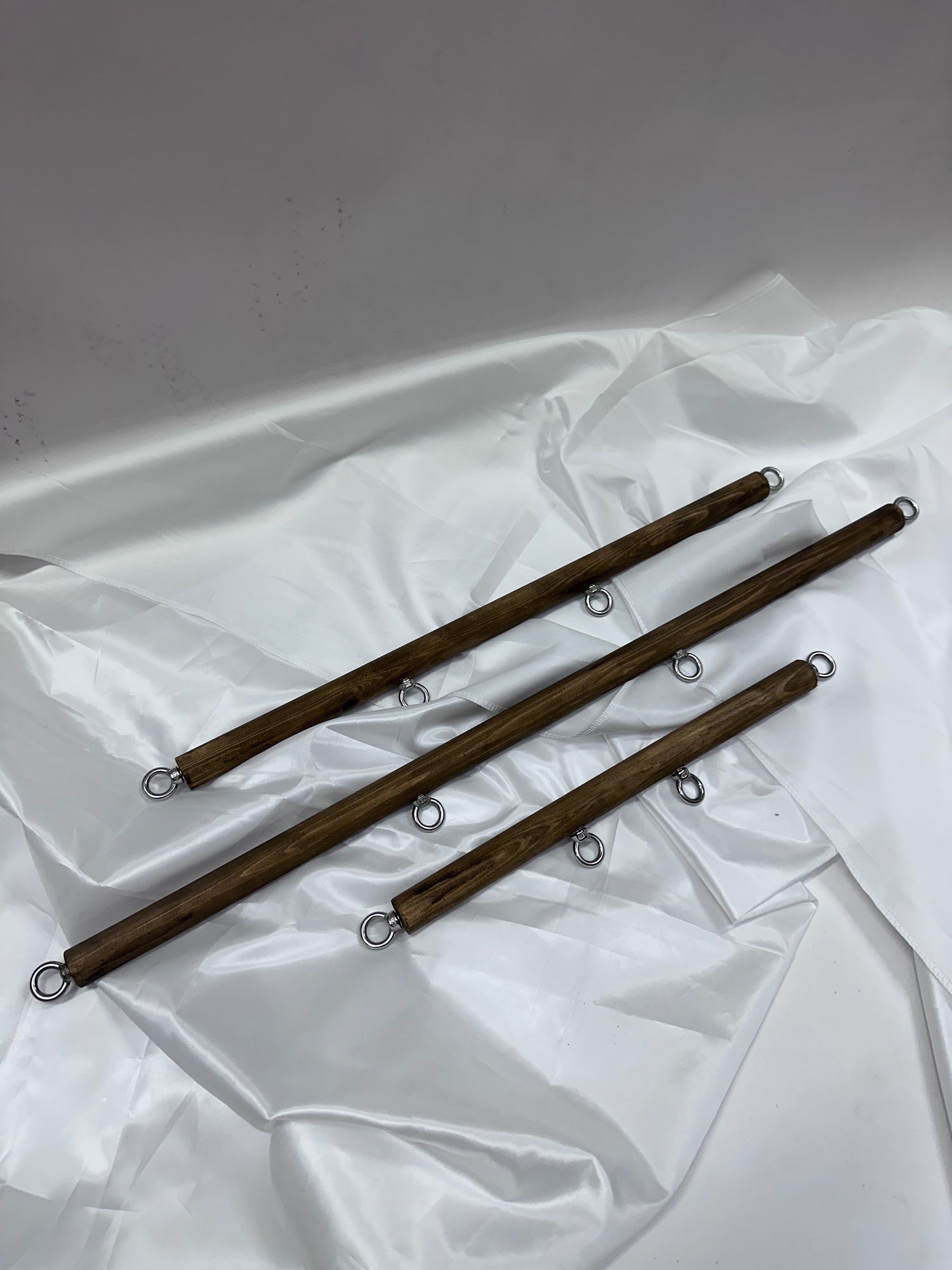 Solid wood spreader bar with metal attachment rings, available in fixed lengths (40, 60, 80 cm), designed for wrist or ankle restraint in BDSM play