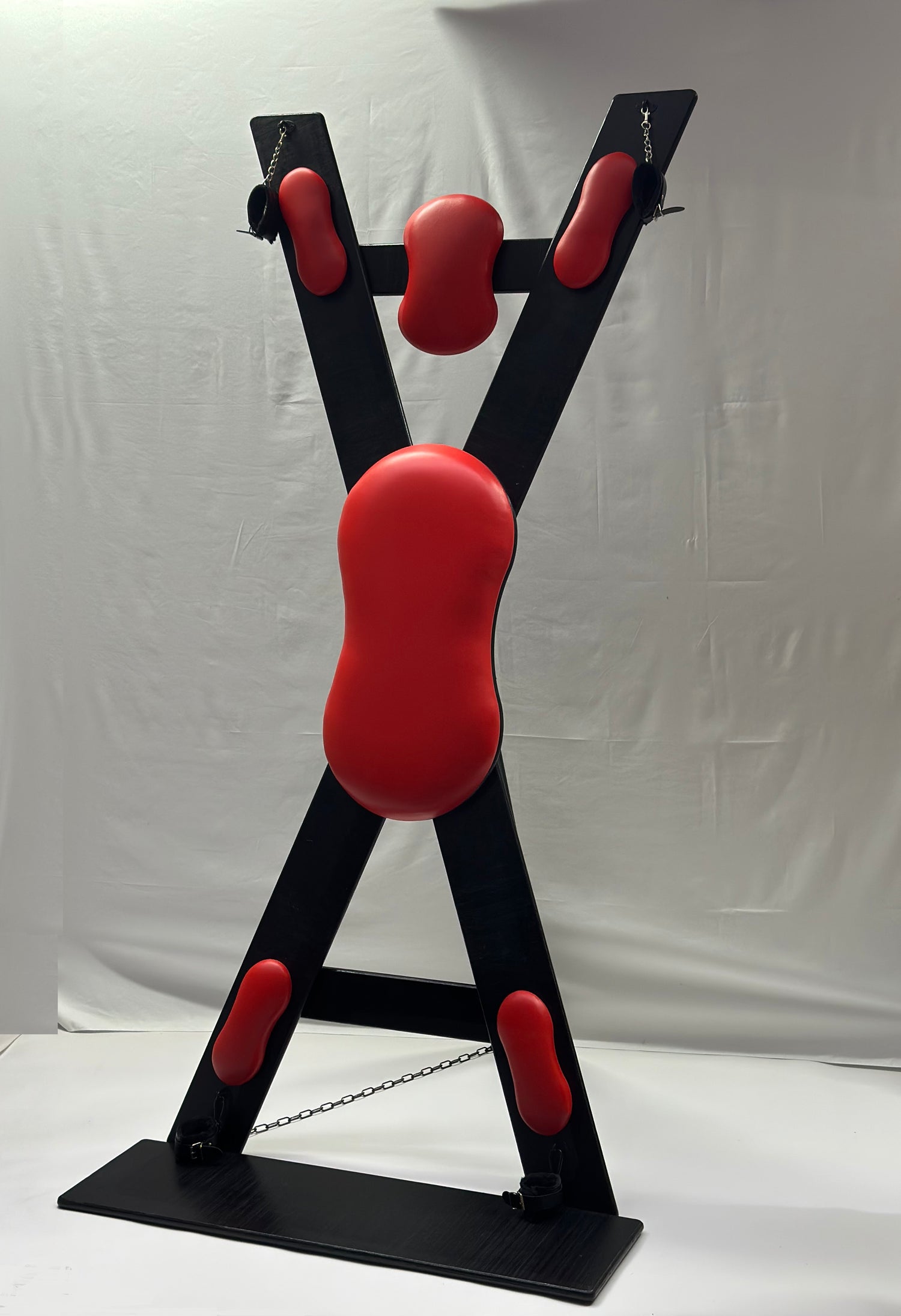 St. Andrew’s Cross made of hardwood with black padded cushions, adjustable restraints, and quick-release hinges for easy storage.