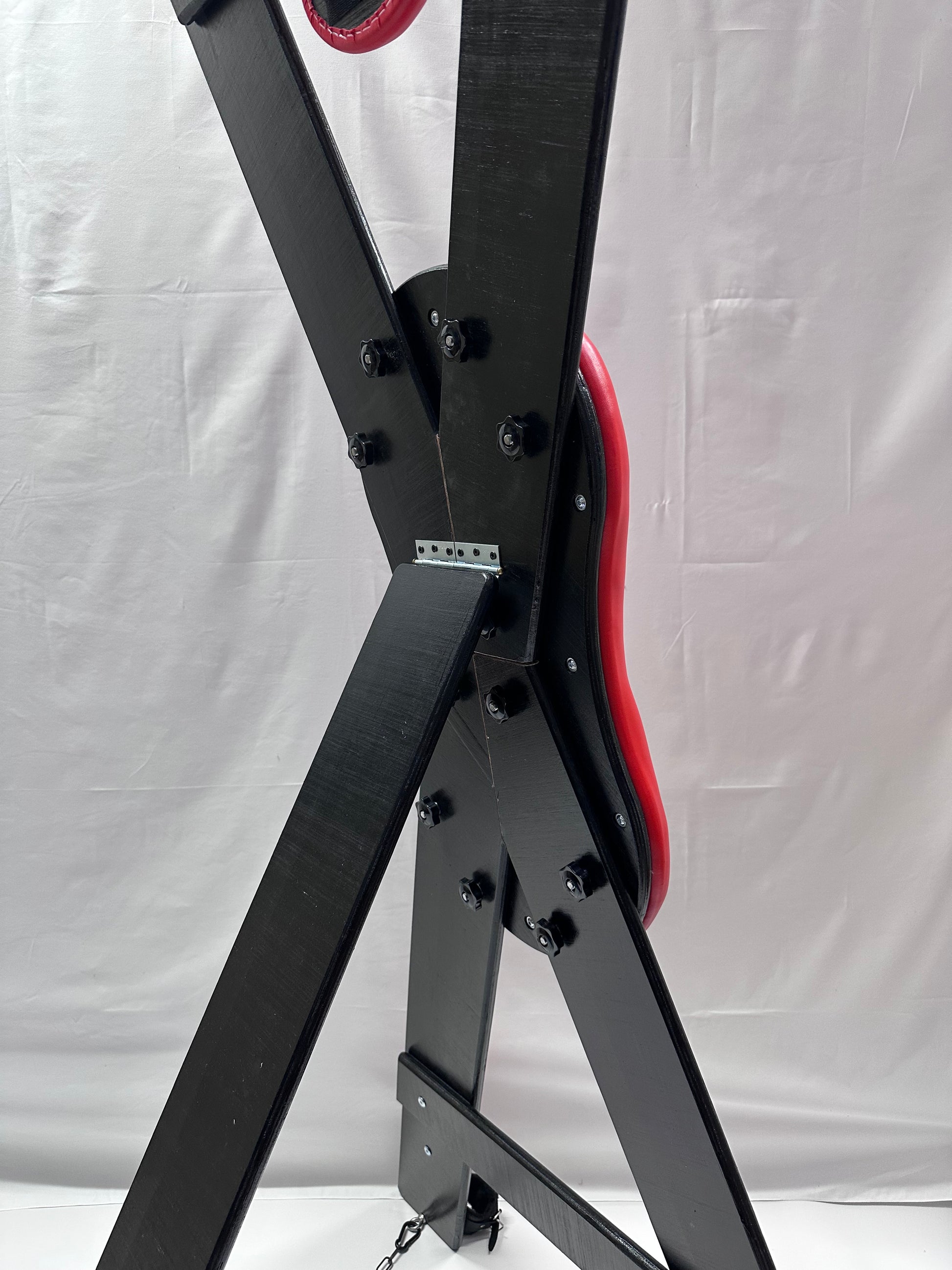 St. Andrew’s Cross made of hardwood with black padded cushions, adjustable restraints, and quick-release hinges for easy storage.
