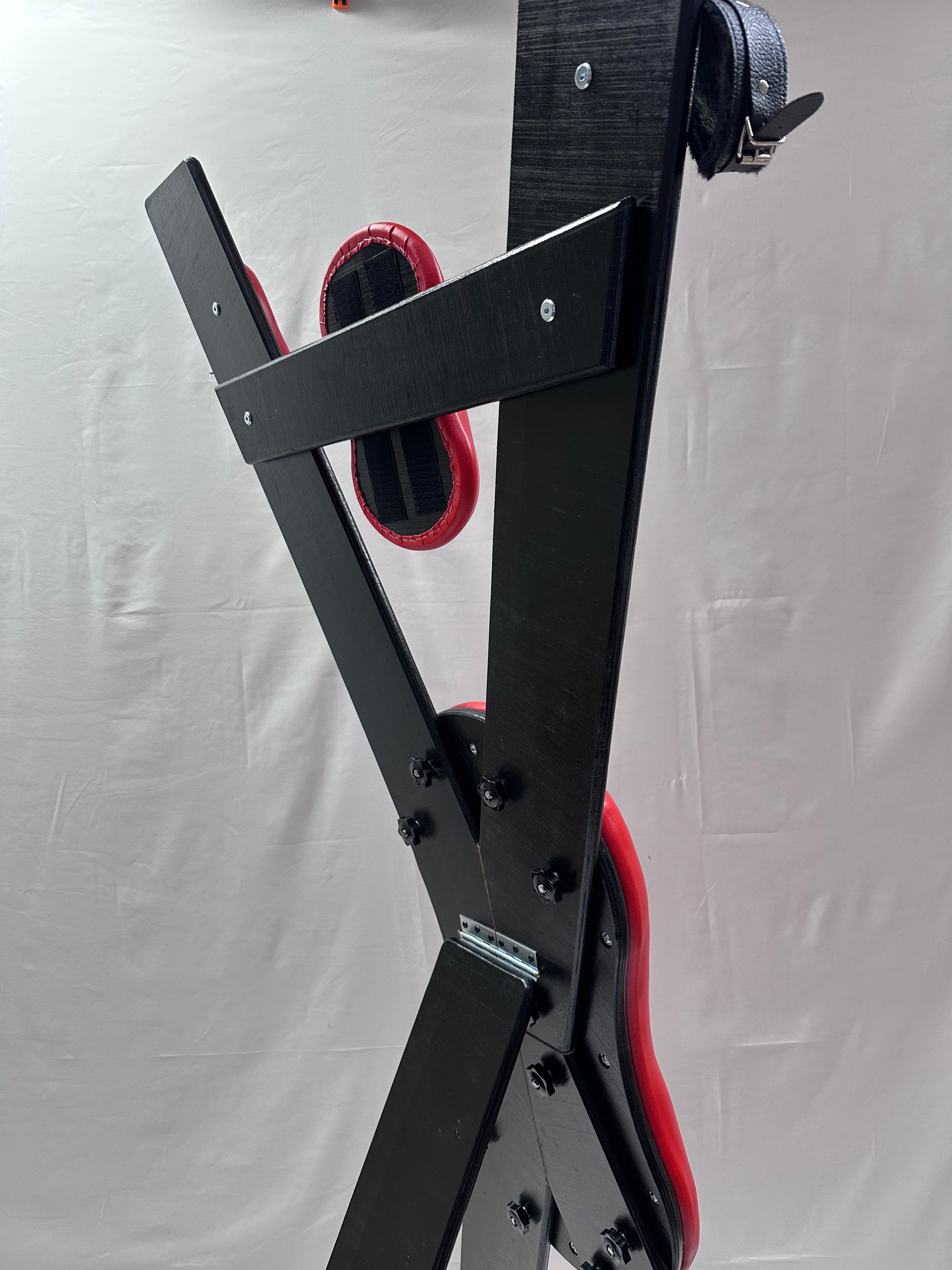 St. Andrew’s Cross made of hardwood with black padded cushions, adjustable restraints, and quick-release hinges for easy storage.
