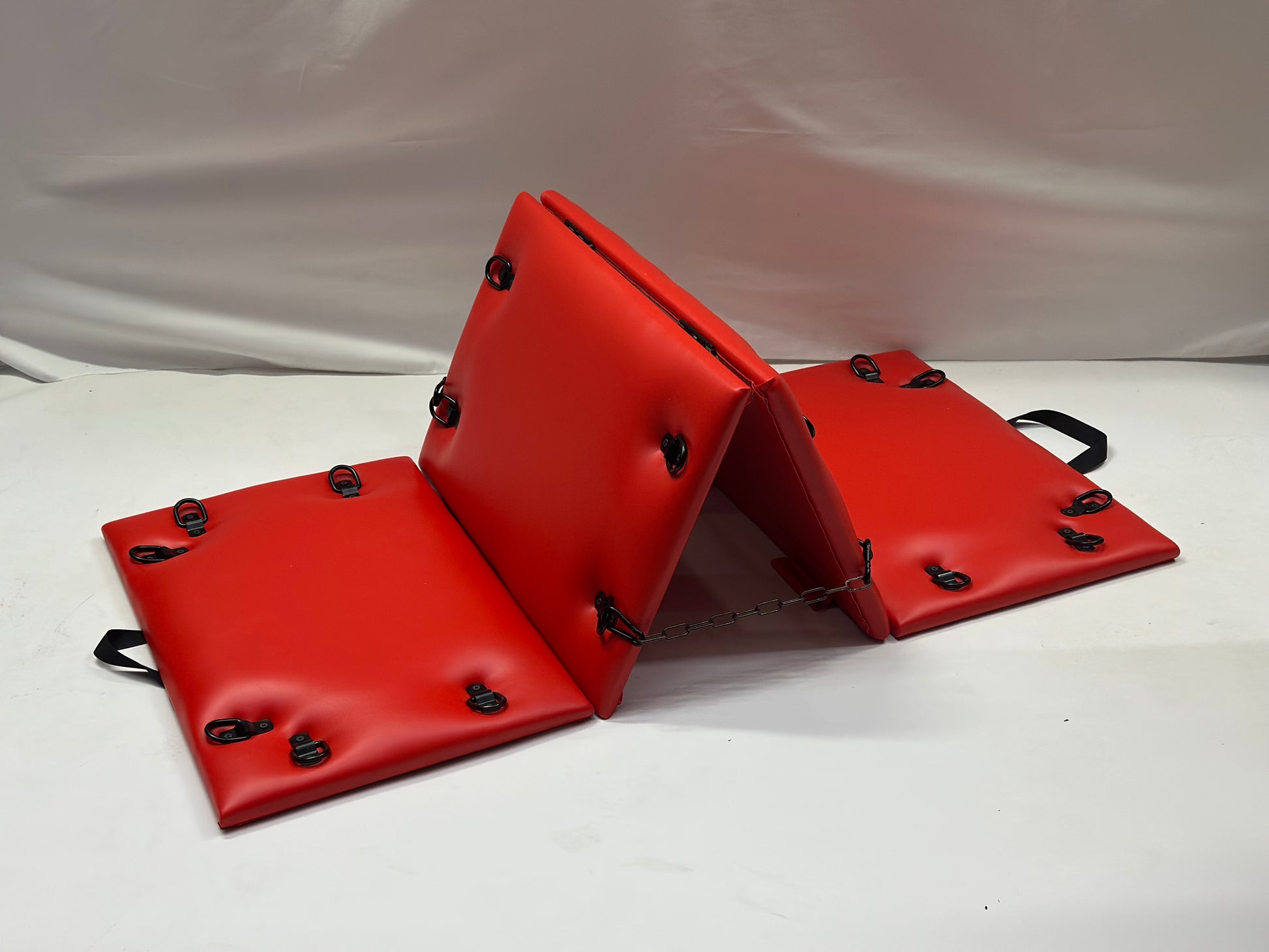 Foldable faux leather spanking bench in black with metal restraint hooks, portable BDSM furniture for bondage play.