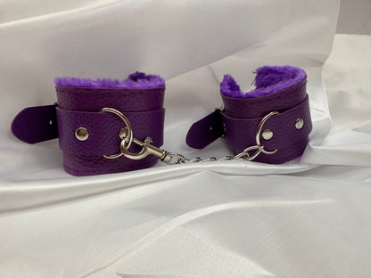 Purple soft faux leather handcuffs with adjustable buckle closure and sturdy metal hardware, perfect for BDSM, roleplay, and cosplay.