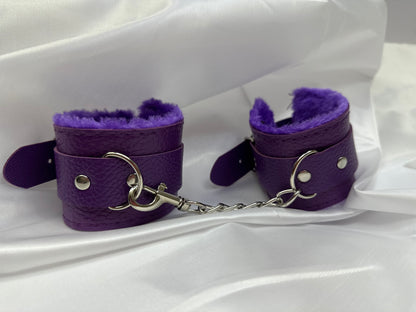 Purple soft faux leather handcuffs with adjustable buckle closure and sturdy metal hardware, perfect for BDSM, roleplay, and cosplay.